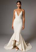 White wedding dress with a deep neckline and mermaid tail on a gray background